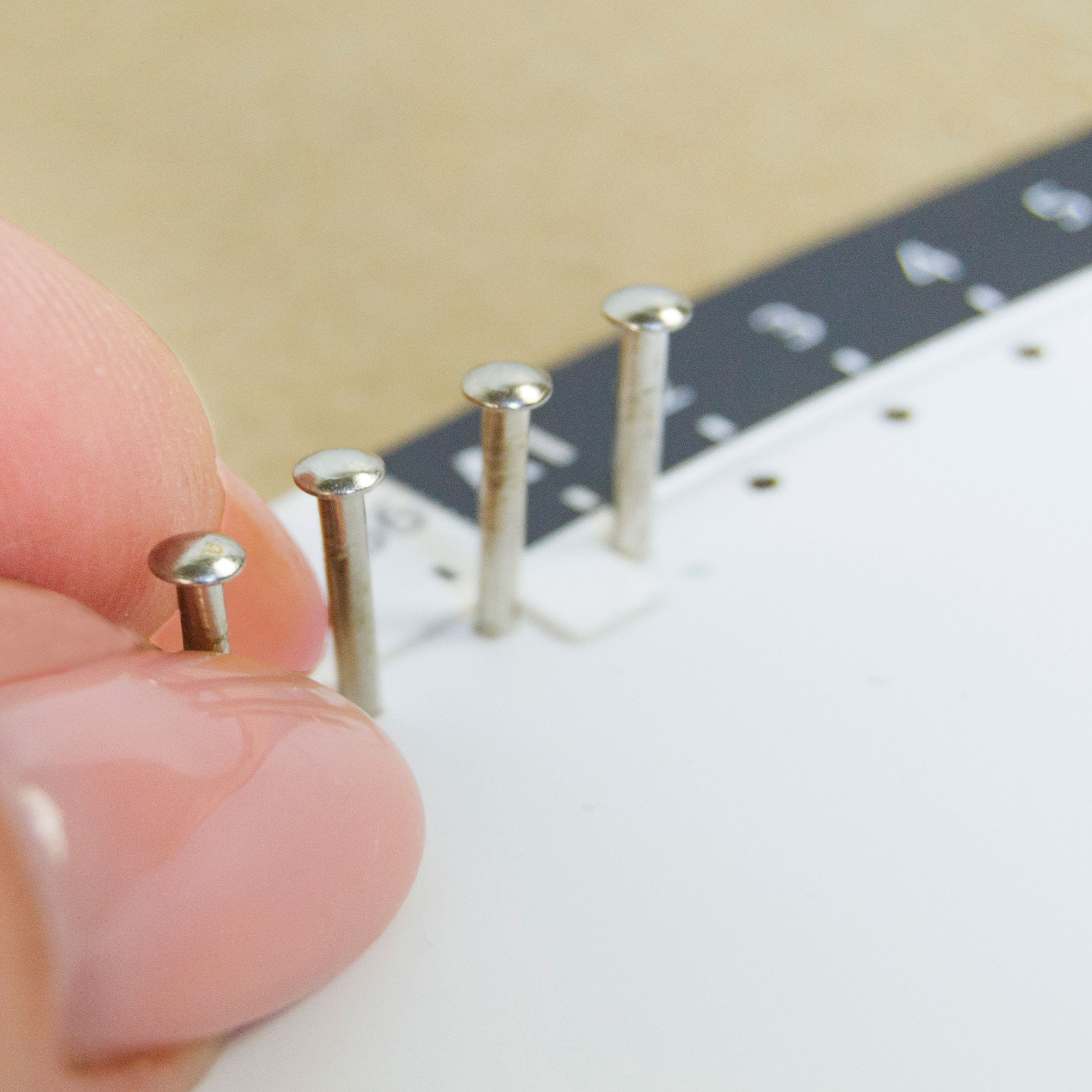 Placing metal nails into a pre-marked circular string art base during assembly