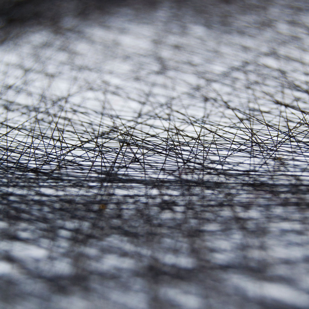 Close-up of intersecting black threads creating a detailed string art texture